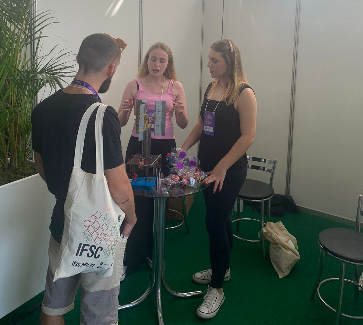 Estudantes Milena e Cecília falando da mini turbina eólica, durante a Feira de Inovação