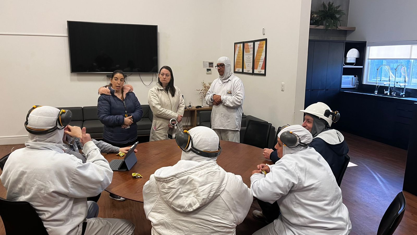 Professora Lara explicando, com auxílio de intérprete de Libras, sobre etapa prática de sua tese de doutorado com colaboradores da Aurora Coop